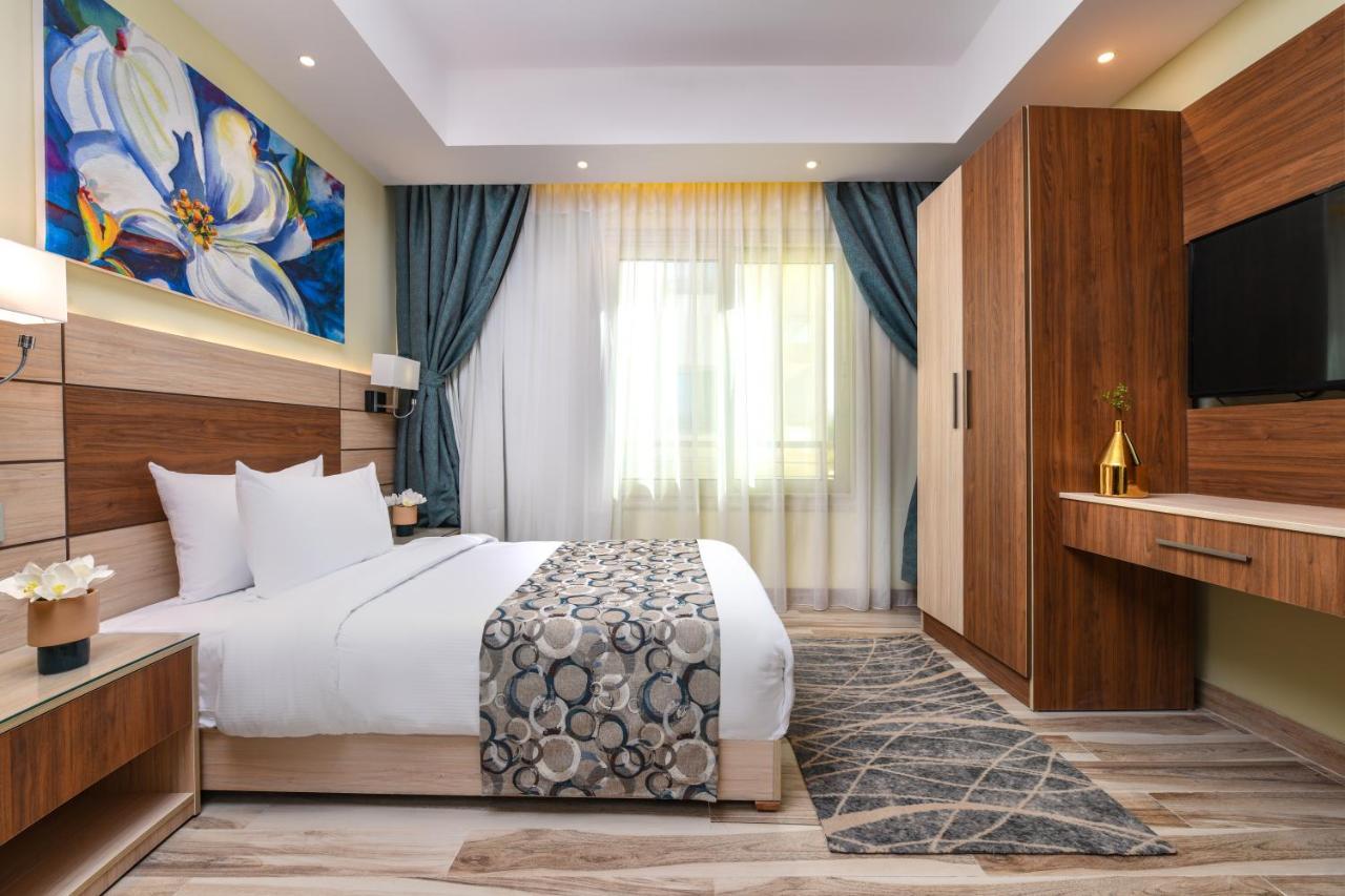 Tolip Resort El Galala Majestic Ain Sukhna Exterior photo The photo shows a well-designed hotel room. It features a comfortable bed with a decorative bedspread and two pillows. There are soft curtains framing a window that lets in natural light. On one side, there is a colorful piece of artwork hanging on t