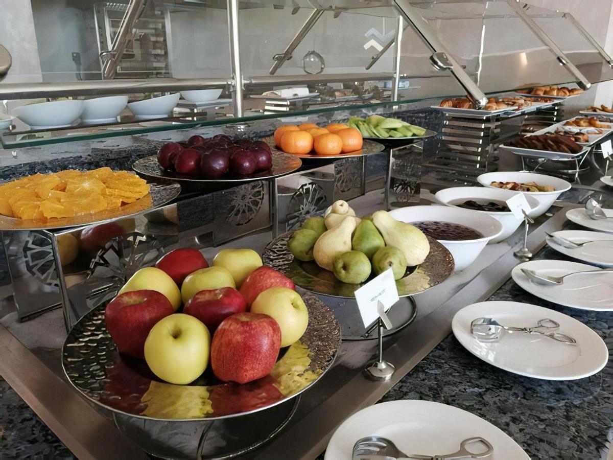 Tolip Resort El Galala Majestic Ain Sukhna Exterior photo The photo displays a buffet setup featuring an assortment of fresh fruits arranged on several tiered trays. There are red and green apples, pears, grapes, and oranges. Adjacent to the fruit display, there are several bowls containing various other fo