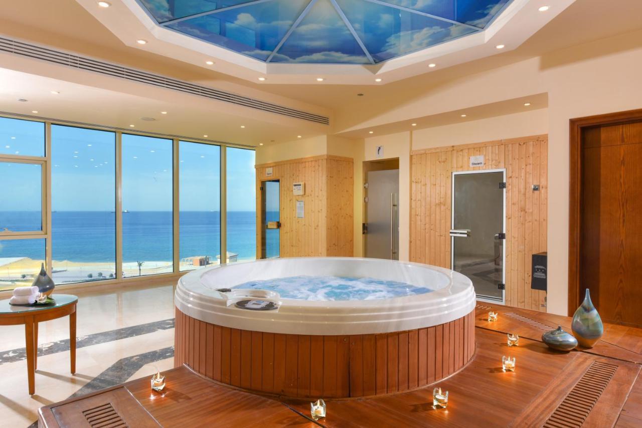 Tolip Resort El Galala Majestic Ain Sukhna Exterior photo The photo shows a luxurious spa room featuring a large, round hot tub positioned in the center. The walls are mostly glass, offering a stunning view of the ocean. The ceiling has a painted sky, enhancing the serene atmosphere. There are wooden elemen