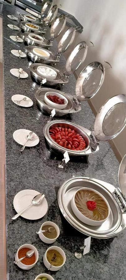 Tolip Resort El Galala Majestic Ain Sukhna Exterior photo The photo shows a buffet setup featuring multiple metal serving trays on a dark granite countertop. One tray contains circular slices of food, possibly sausages or a similar dish, while another bowl holds what appears to be red food items, though it'