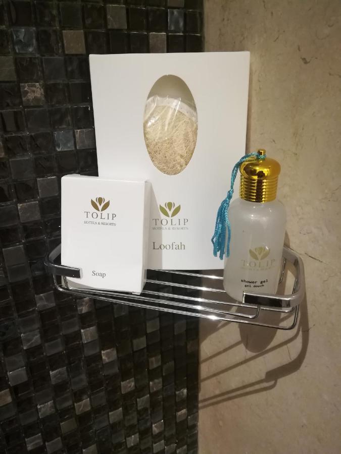 Tolip Resort El Galala Majestic Ain Sukhna Exterior photo The photo shows a small metal shelf containing three items related to personal care. 

1. **Soap**: A white box labeled "TOLIP" with the word "Soap" visible on the front.
2. **Loofah**: A package with the same "TOLIP" branding, containing loofah.
3. 